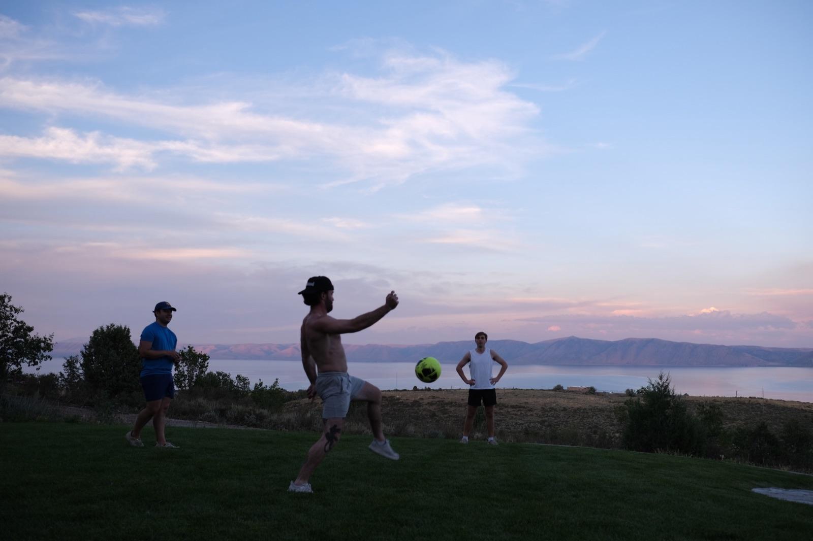 Teammates playing with a ball on the lawn above the lake