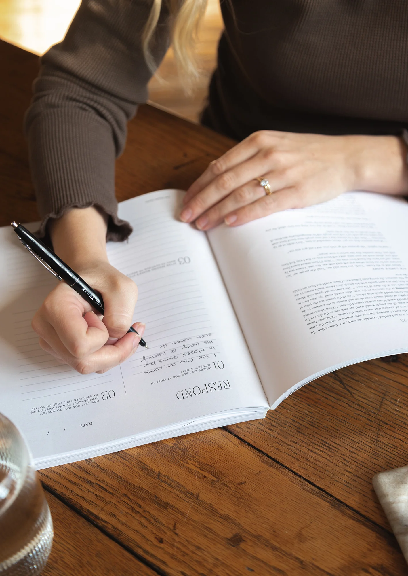 A woman writing in an open journal at a desk