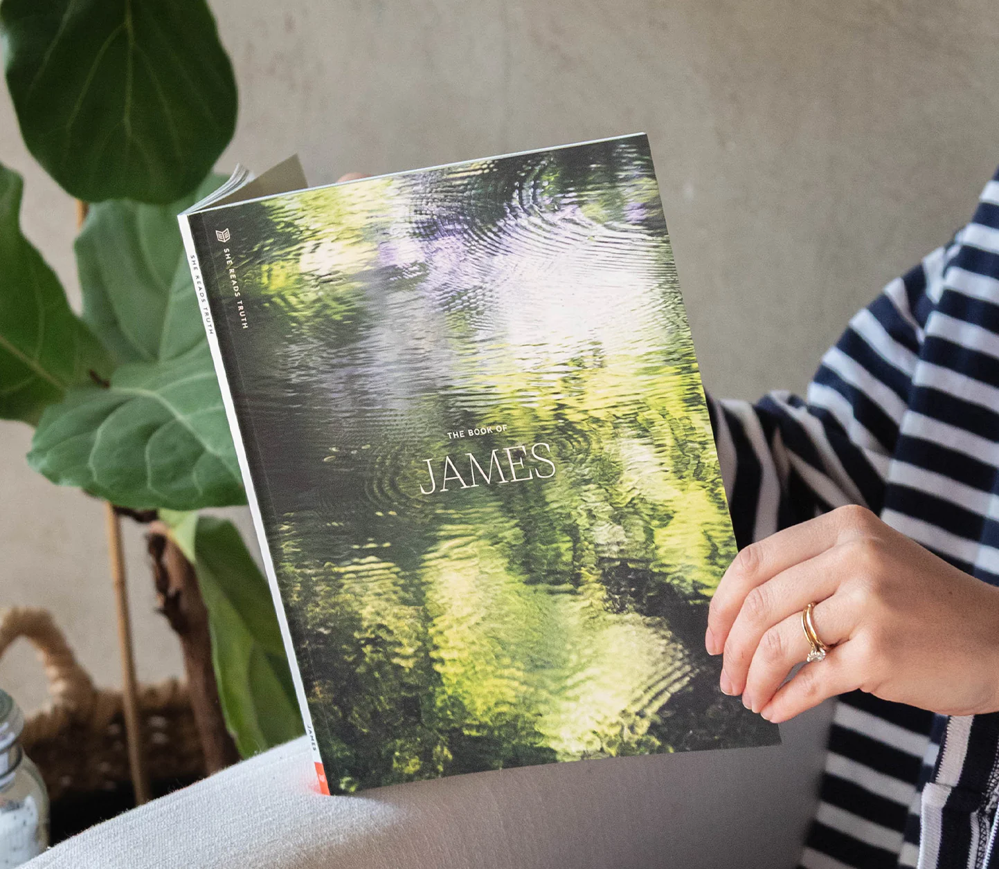 A woman holding an open book that says "The Book of James" on the cover