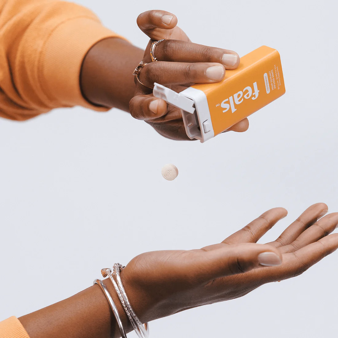 Hands pouring out a mint from an orange can