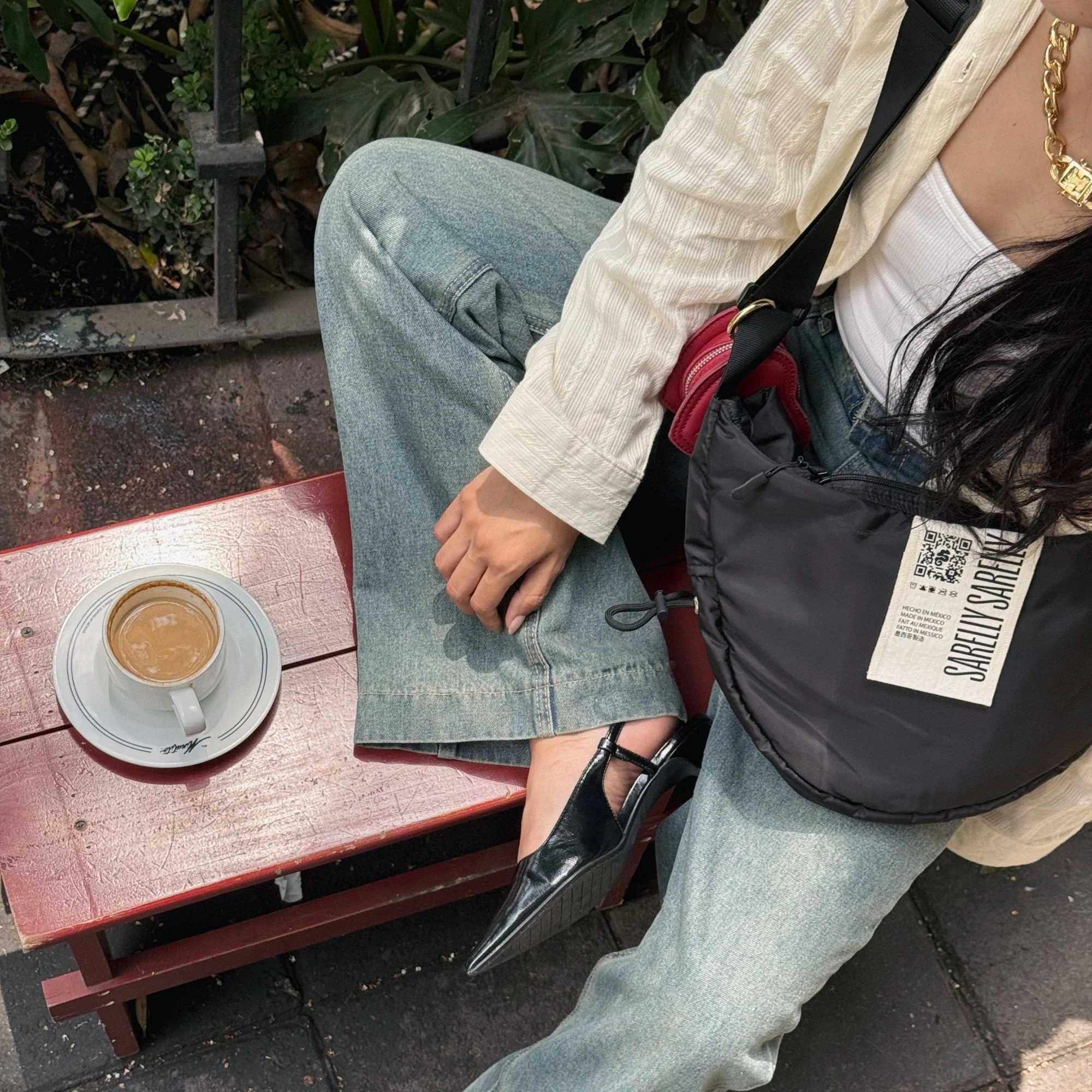 Girl sitting with a coffee outdoors wearing Sarelly products